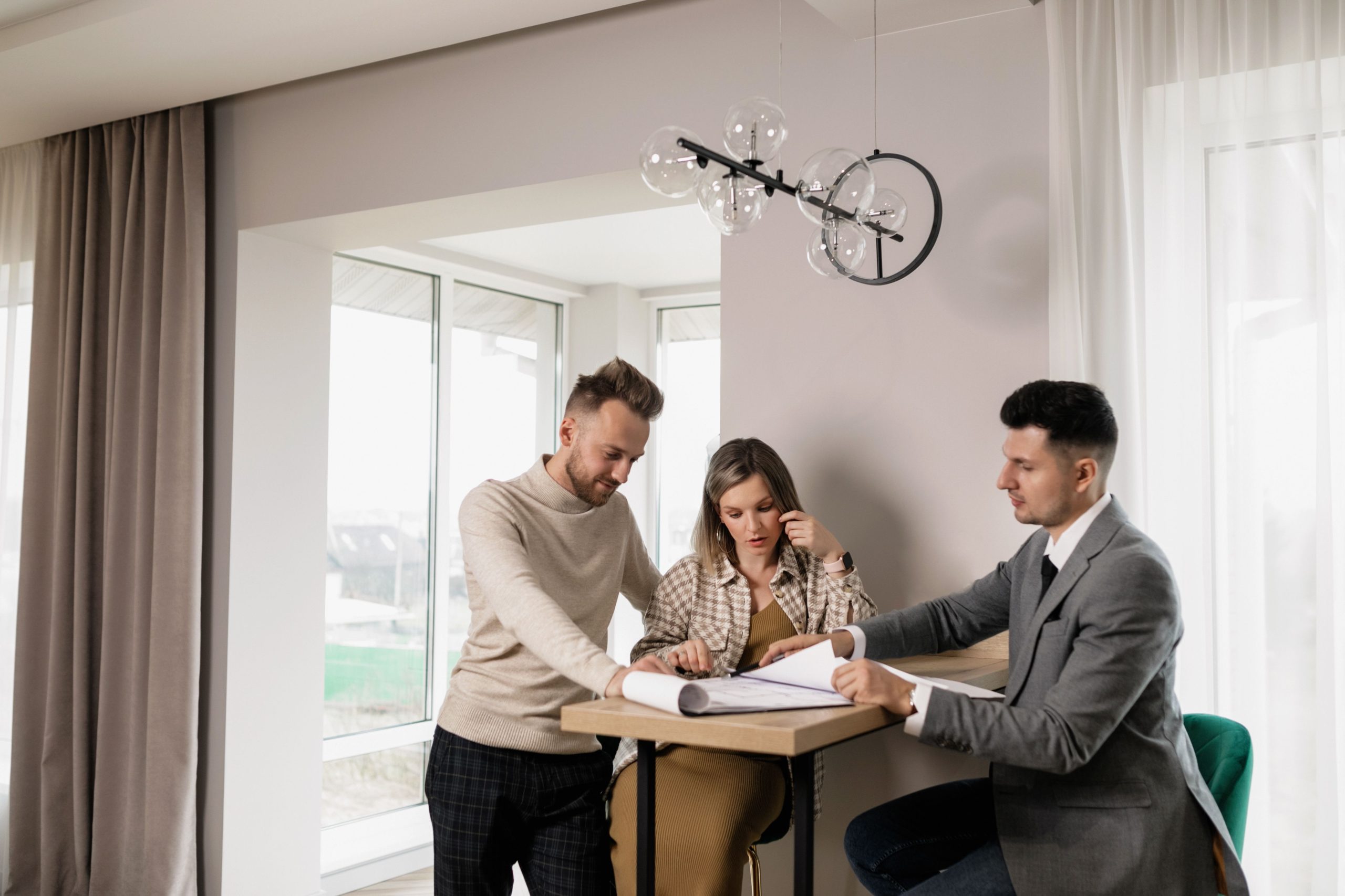Couple consulte agent immobilier avec documents propriété