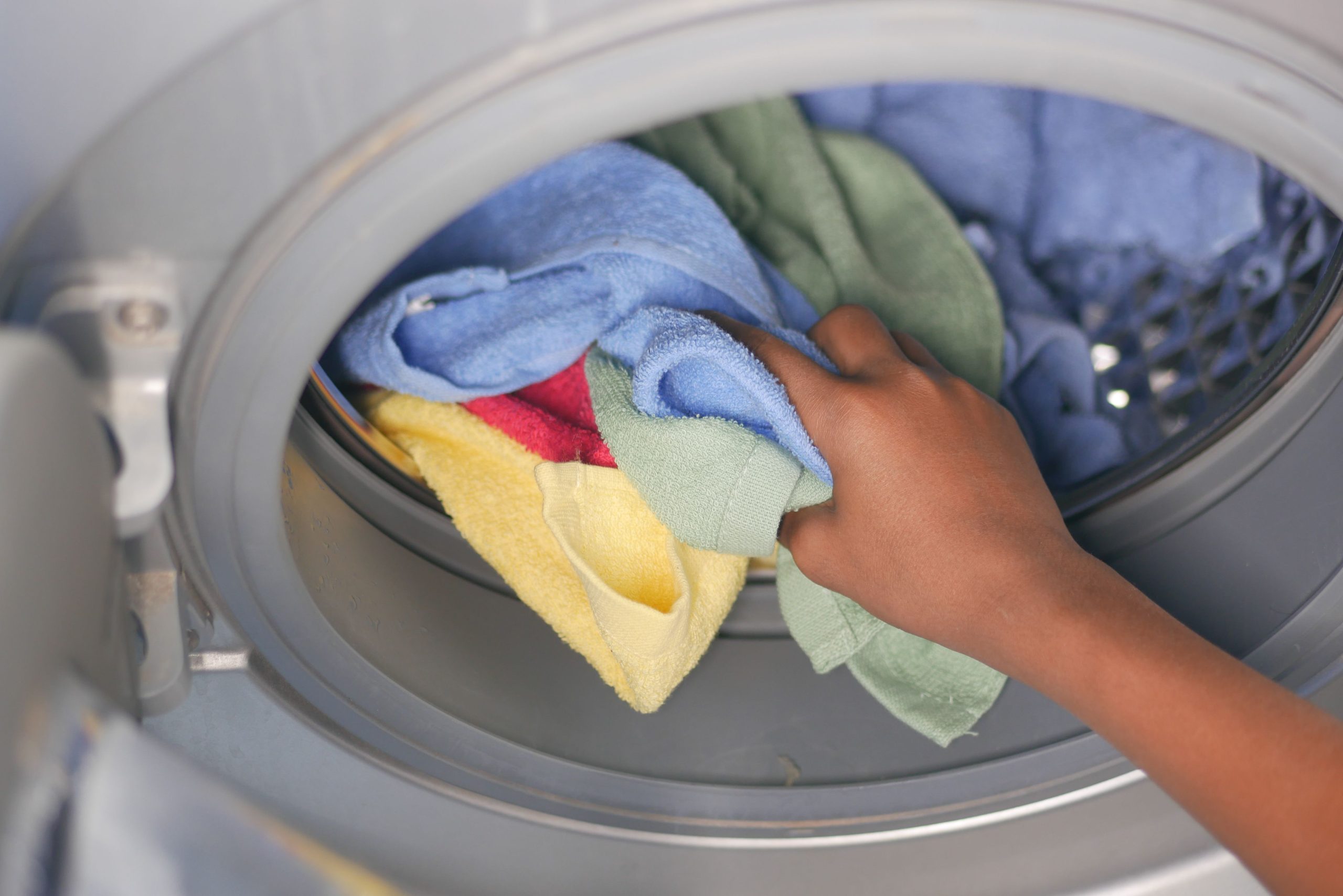 Main qui place du linge dans un lave linge