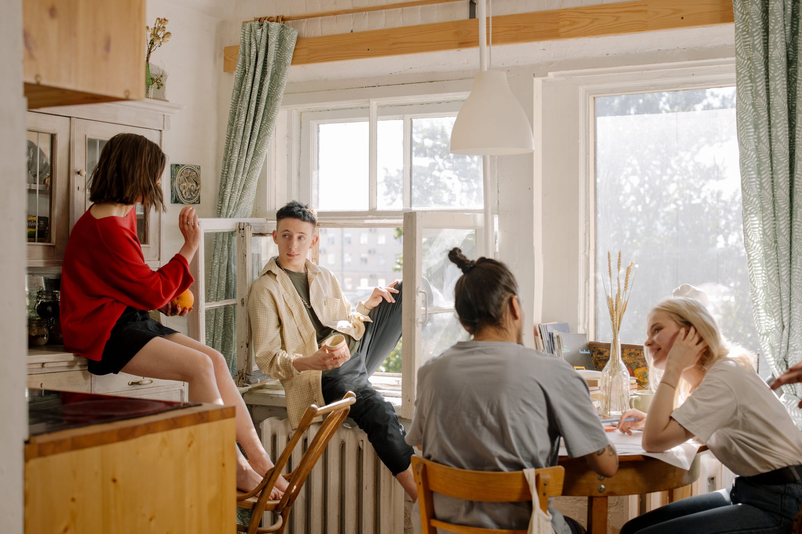 Groupe d'amis discutant dans une cuisine ensoleillée